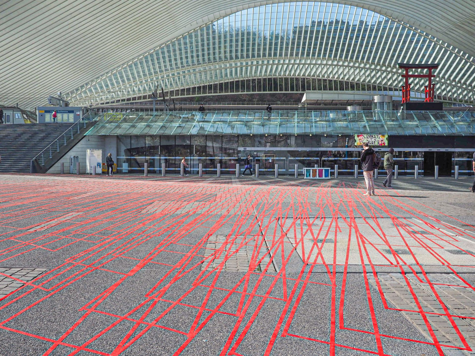 Des dizaines de mètres de ruban adhésif rouge collés par terre devant la gare des Guillemins